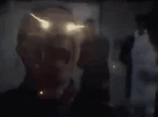 a close up of a man 's face with his mouth open and his eyes glowing in the dark .