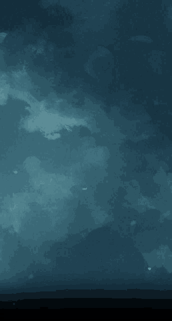 a dark blue sky with white clouds and a few stars
