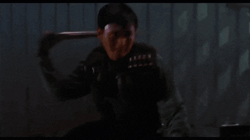 a man is holding a shotgun in front of a pink wall .