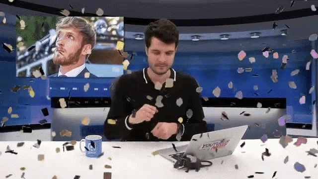 a man sitting at a table with a laptop that says youtube