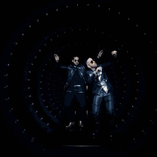 two men are dancing in front of a circular display of lights