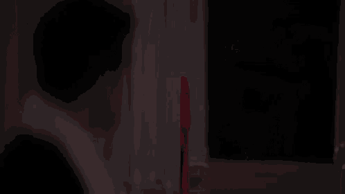 a man in a suit is sitting at a table with a red knife in his hand .