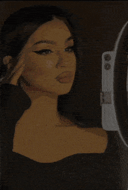 a woman is taking a selfie with a ring light in front of her face