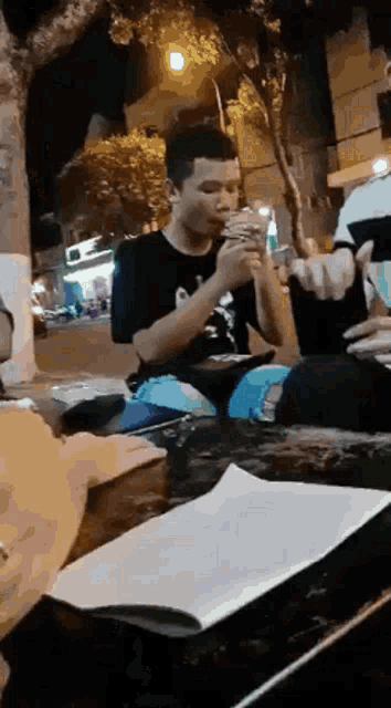 a man is sitting at a table eating a hamburger and drinking a drink .