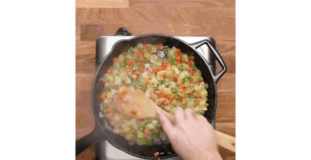 a person is cooking vegetables in a skillet on a stove .