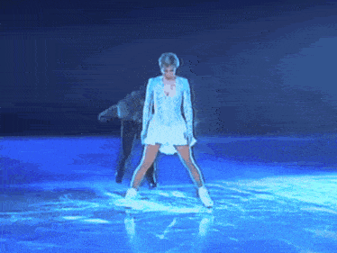 a woman in a white dress is standing on a ice rink