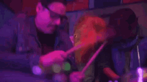 a man is playing a violin in a dark room while a woman looks on .