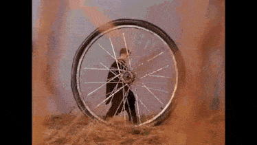 a person is standing in front of a broken bicycle wheel .