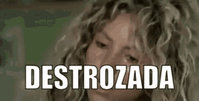 a woman with curly hair is looking at the camera with the word destrozada written on her face .