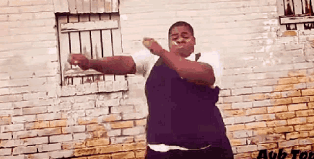 a man is dancing in front of a brick wall with the word aub written on it