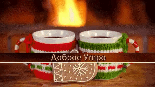 two cups of tea and a gingerbread cookie on a table with a fireplace in the background
