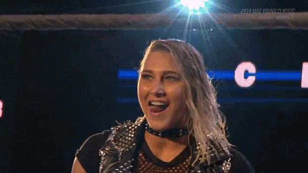 a woman is standing in a wrestling ring with her mouth open and the number 8 behind her .