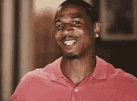 a man in a red shirt is smiling while looking at the camera .