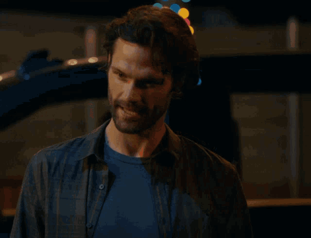 a man in a plaid shirt has his hand on his hair