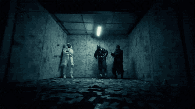 a group of people are standing in a dark room with a light on the ceiling