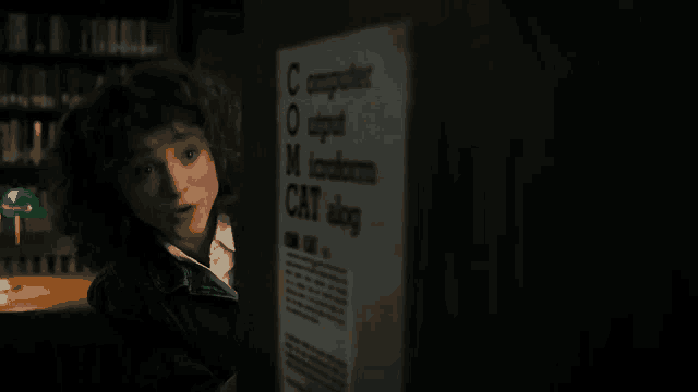 a young girl is standing in front of a computer in a dark room .