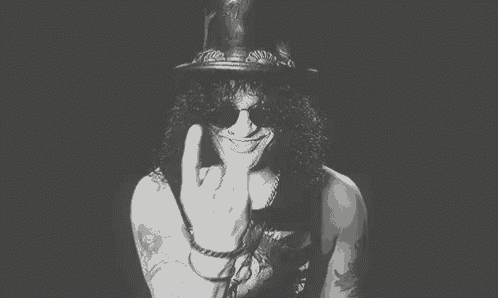 a black and white photo of a man wearing a hat and sunglasses covering his mouth with his hands .