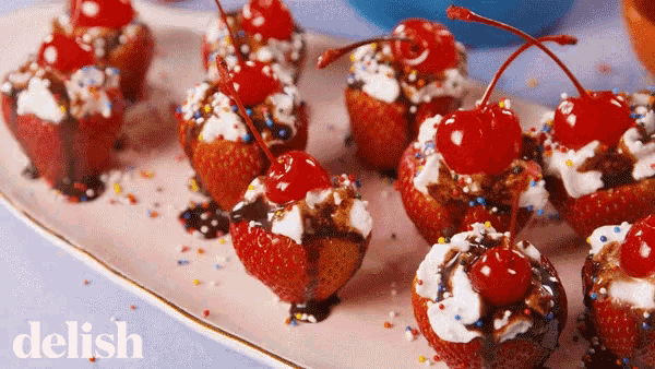 a plate of strawberry cupcakes with cherries and whipped cream on top