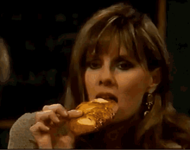 a woman covering her mouth with her hands while eating a hamburger