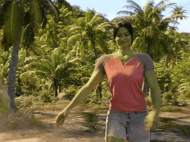 a woman with green arms and legs is walking through a jungle