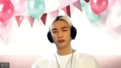 a young man wearing headphones is sitting in front of balloons and flags .