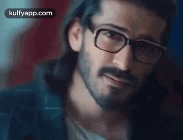 a man with a beard and glasses is smiling .