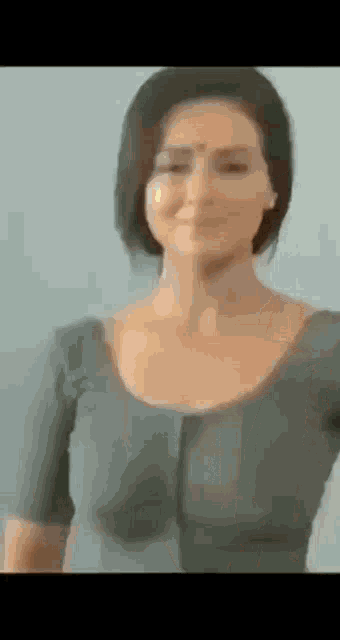 a woman is standing in front of a blue wall wearing a gray shirt .