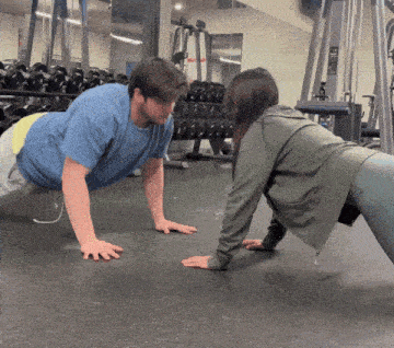 a man and a woman are doing push ups together in a gym