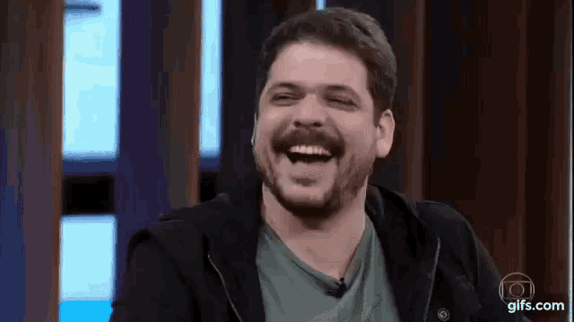 a man with a beard and mustache is laughing on a stage .