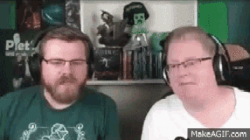 two men wearing headphones and glasses are sitting next to each other in front of a green screen .