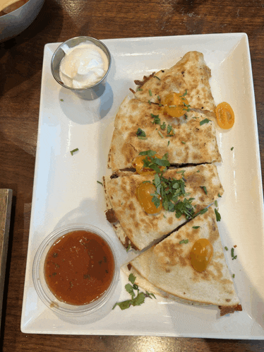 a quesadilla with tomatoes and sour cream on a plate