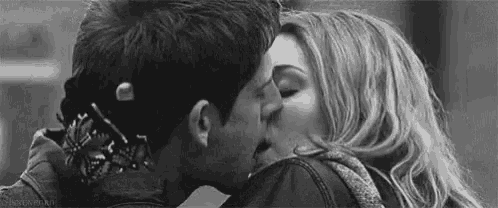 a black and white photo of a man and woman kissing each other .