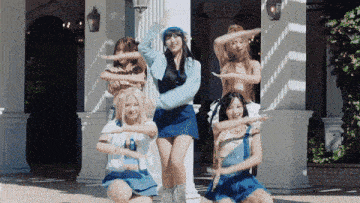 a group of women are dancing in front of a white building
