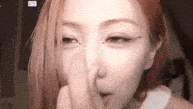 a woman is touching her nose with her finger .