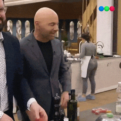 a bald man in a suit is standing in a kitchen