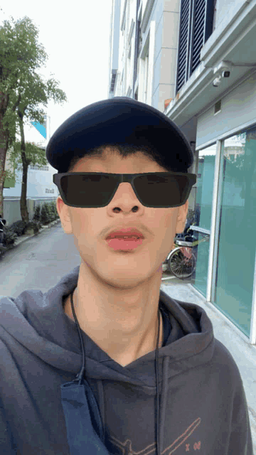 a man wearing sunglasses and a hat has the number 90 on his hoodie