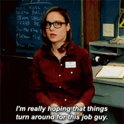 a woman wearing glasses is sitting in front of a blackboard .