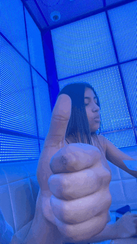 a woman giving a thumbs up in front of a blue background