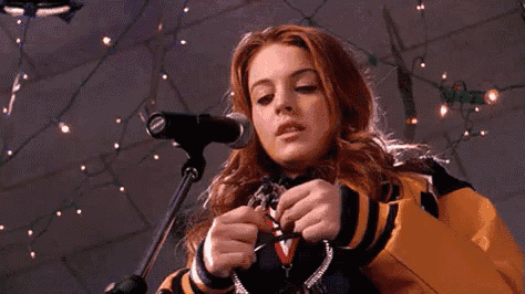 a woman in a yellow and black jacket is singing into a microphone while holding a key .