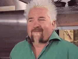 a man with a beard and a mohawk is wearing a green shirt and making a funny face .