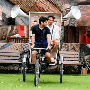 two men are riding a bicycle with a sign that says vote