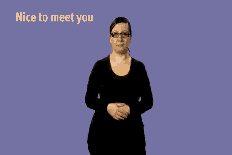 a woman in a black dress and glasses is making a sign language gesture that says `` nice to meet you '' .