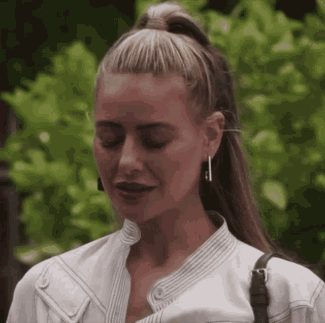 a woman wearing a white jacket and earrings is looking down