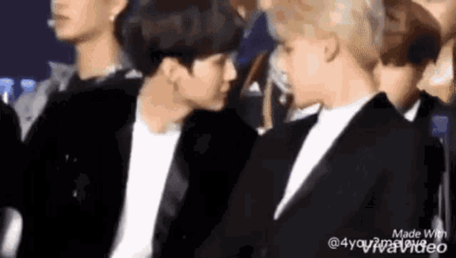 two men are sitting next to each other in a crowd .