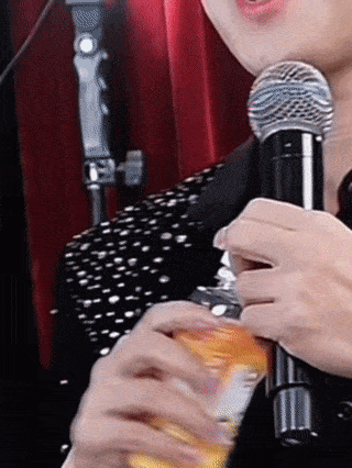 a person holding a microphone and a bottle of orange juice