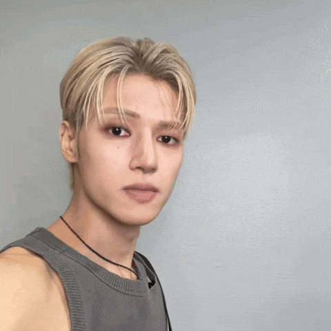 a man with blonde hair is wearing a grey tank top and a black necklace