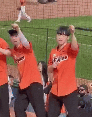 a group of people in orange eagles jerseys are dancing on a baseball field
