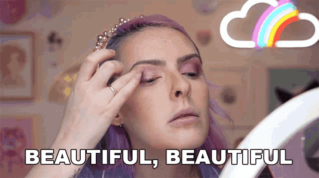 a woman with purple hair is applying eye shadow and the words beautiful beautiful are above her