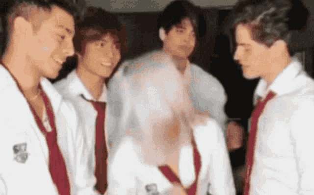 a group of young men wearing white shirts and red ties are standing next to each other