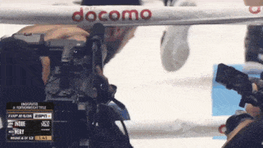 a boxing match is being filmed with a docomo advertisement in the background